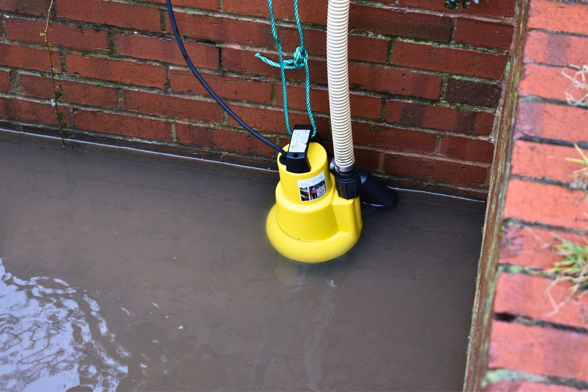 AMA Drainer 301 Submersible Pump pictured in flood water with float arm and hose attached