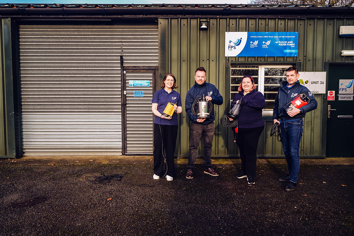Team of staff holding water pumps outside a warehouse