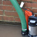 Sump pump with green hose against a brick wall