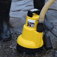 AMA Drainer Automatic Submersible Water Pump in water with a person wearing rubber boots in the background