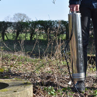 Person holding a Acuabig well pump with trees and grass in the background