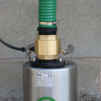 Close-up of a metal water pump with a brass non return fitted, black hose tail and green suction and delivery pump photographed against a concrete wall.