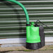 EGO GI Puddle pump with suction delivery hose agaisnt a green shutter door 