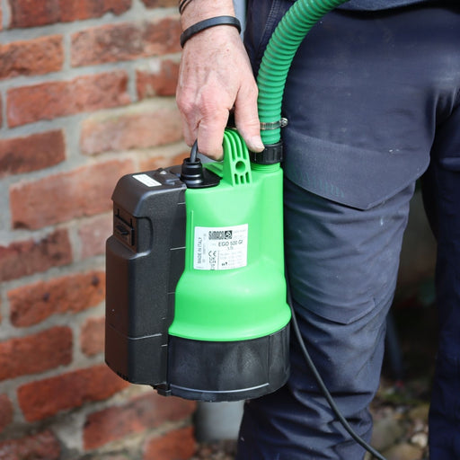 Person holding a EGO GI LS water pump against a brick wall