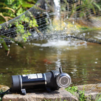 FL Demand water pump on a stone ledge with a pond and water features in the background