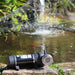 FL Demand water pump on a stone ledge with a pond and water features in the background