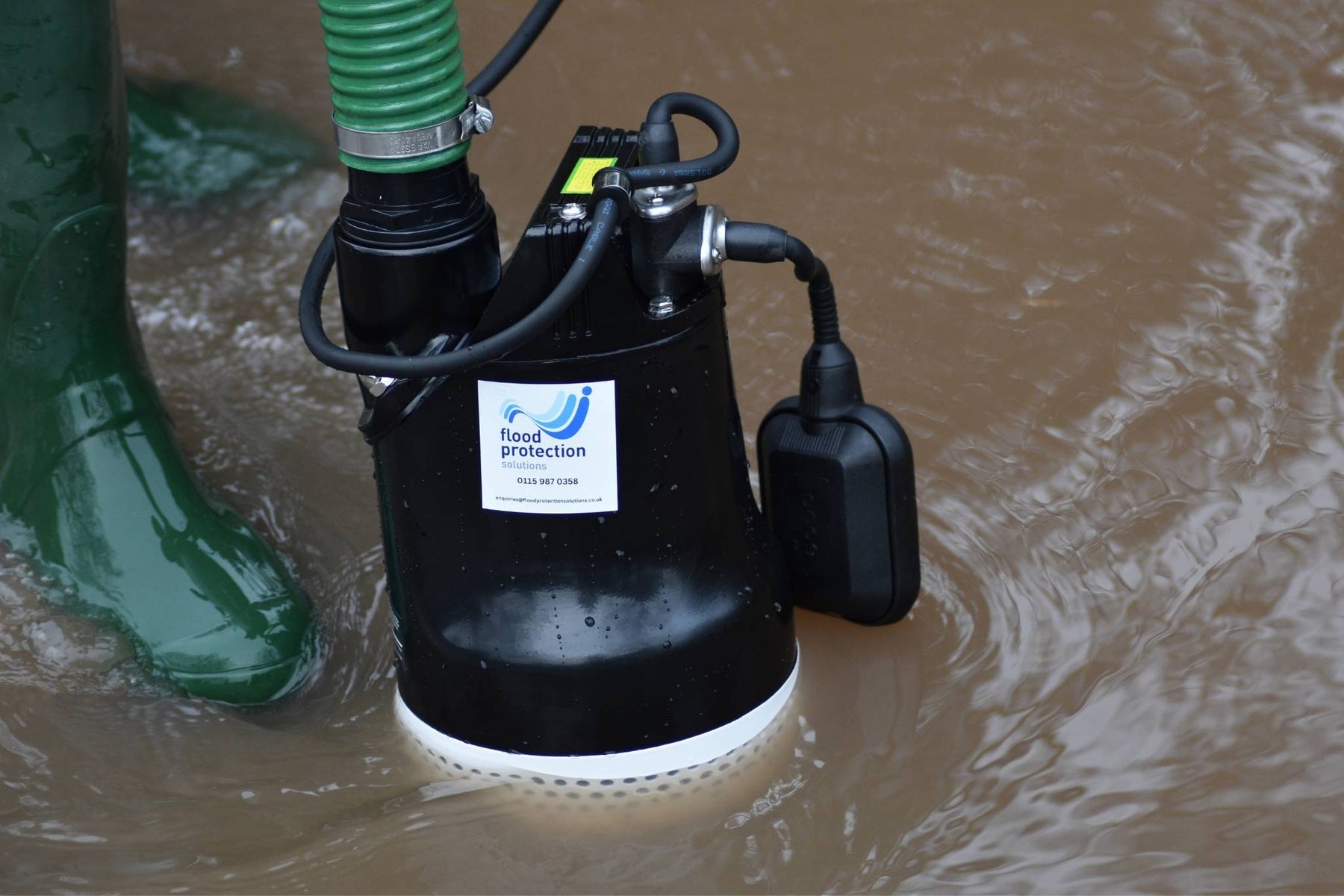 Submersible pump in floodwaters with a boot nearby, featuring 'Flood Protection' branding.