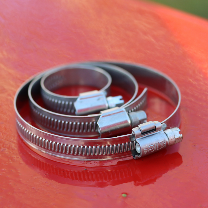 Metal hose clips on a red surface