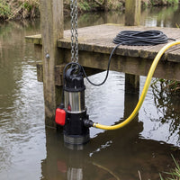 a water pump being lowered into a river by a chain off a jetty for irrigation