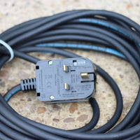 Coiled heavy duty power cable with a 230v plug on a textured surface