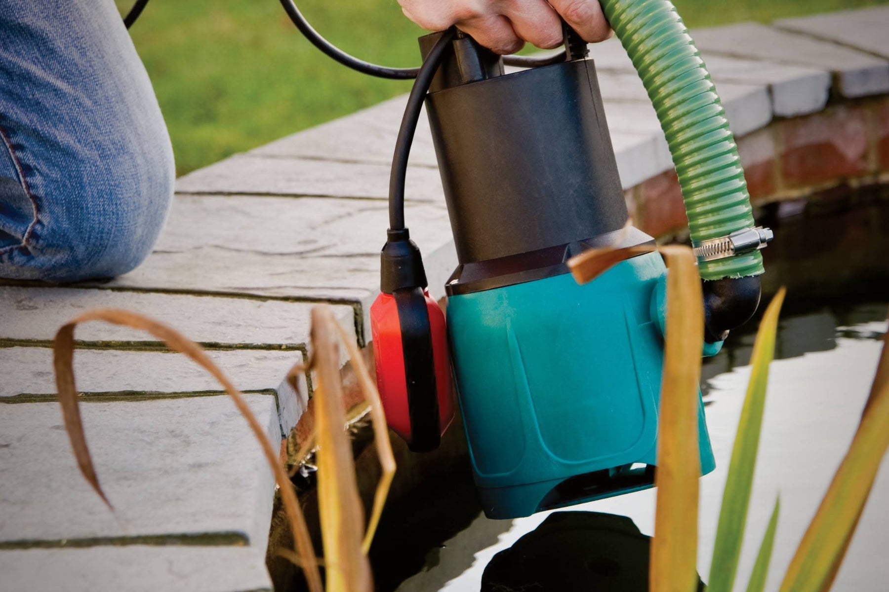 Person installing a pond pump into a pond