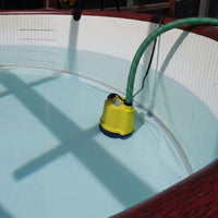 A yellow puddle pump with a green flexible hose, shown inside a hot tub