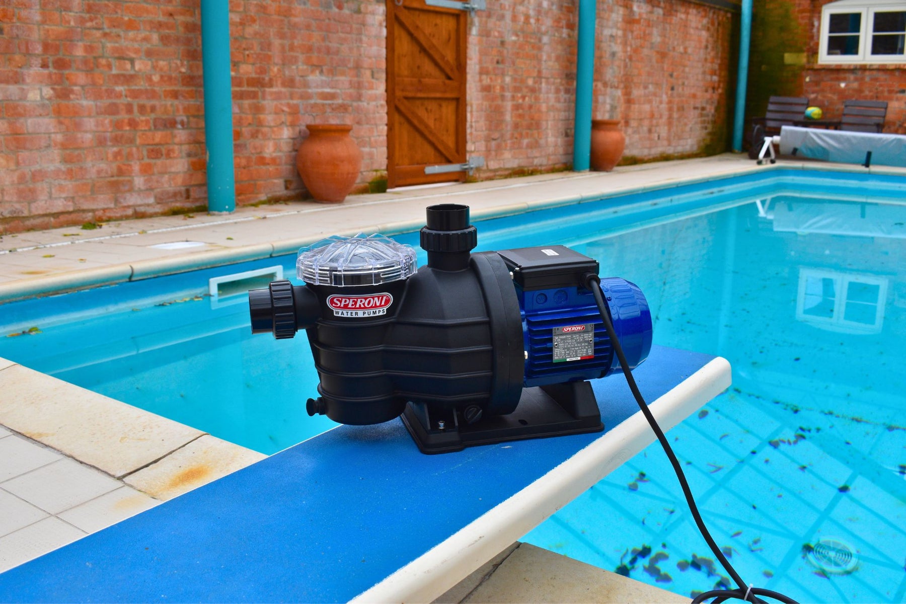 Speroni SWIMM pool pump next to outdoor residential swimming pool