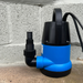 Blue and black submersible pump against a concrete wall.