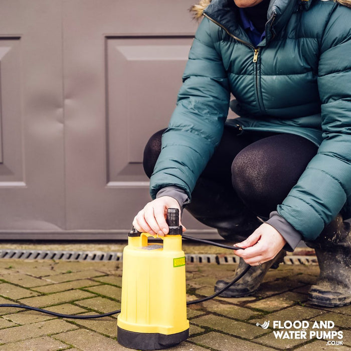 Yellow Stream SPP Puddle Pump positioned on a driveway, showcasing its cost-effective solution for efficient water removal