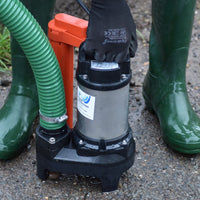 Person wearing green wellies with a Tsurumi POMA Submersible Automatic Pump and green hose on a concrete surface