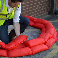 Person in a high-visibility vest working with red hydro snakes on a street.