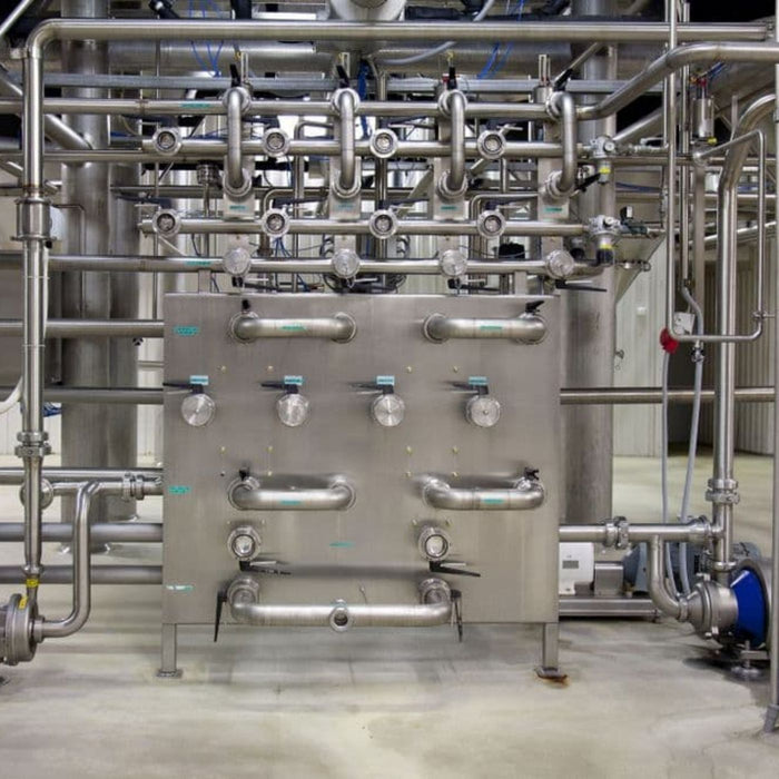 Stainless steel industrial equipment with pipes and valves in a factory setting