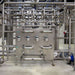 Stainless steel industrial equipment with pipes and valves in a factory setting